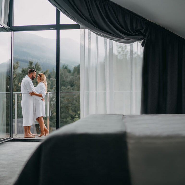 Para w objęciach na balkonie hotelowym w górach.